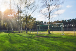 Symbolic picture lockdown, cordoned off soccer field, soccer goal in front of forest, deserted, selective focus Symbolic picture lockdown, cordoned off soccer field, soccer goal in front of forest, deserted, selective focus